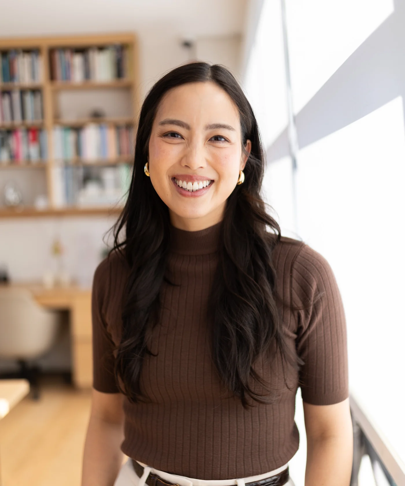 Lorraine K. Lee smiling in a bright office with bookshelves behind her