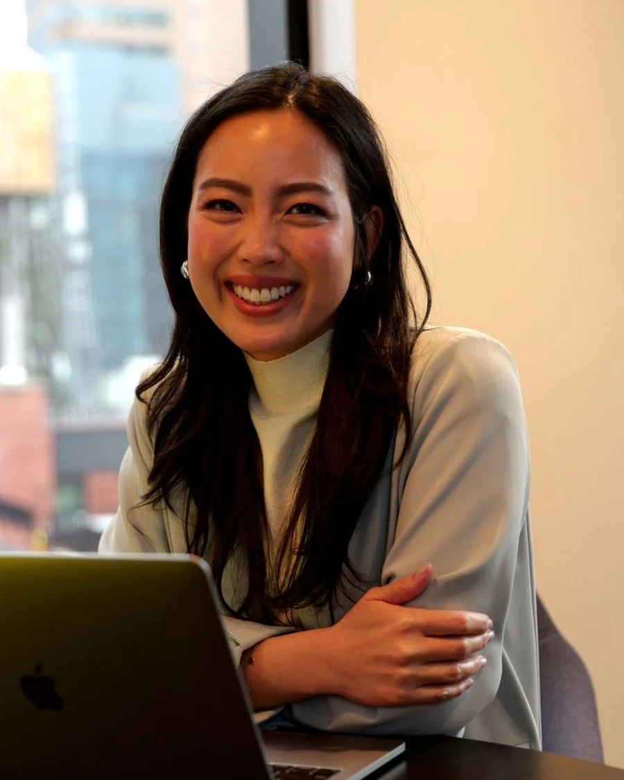 Lorraine K. Lee smiling at her laptop in a sunny office